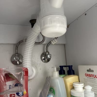 צנרת מתחת לכיור עם מוצרי ניקוי