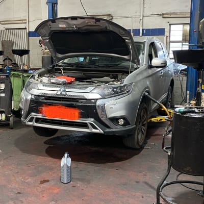 רכב במוסך עם מכסה מנוע פתוח וכלי עבודה סביבו