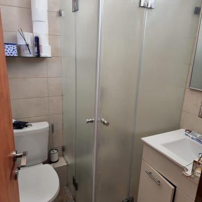 מקלחון זכוכית עם דלתות מתכת בחדר אמבטיה