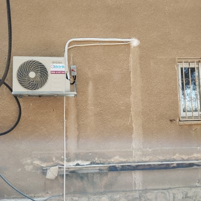 יחידת מיזוג אוויר מותקנת על קיר חיצוני עם צינורות חשמל