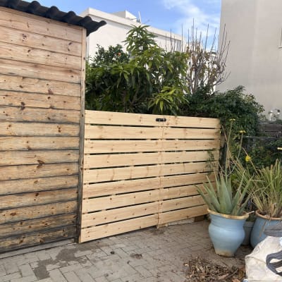 גדר עץ חדשה ליד עציצים וצמחייה בגינה