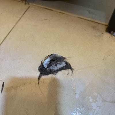 שיער ולכלוך על רצפה ליד צינור מתכת