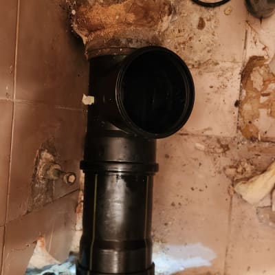 צינור שחור מותקן בקיר עם אריחים שבורים