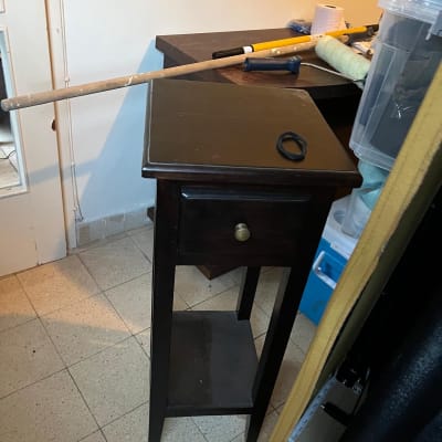 שידת עץ כהה עם מגירה יחידה בתוך חדר במבנה מגורים