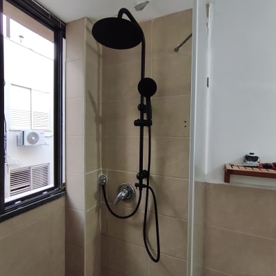 מקלחת עם ראש מקלחת שחור על קיר אריחים