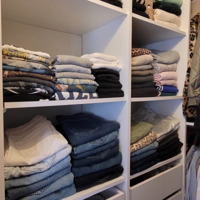 בגדים מקופלים בארון לבן עם מדפים ומגירות