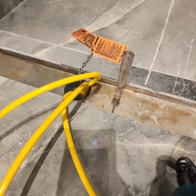 כבלים צהובים, מברג ותג אזהרה על רצפה אפורה