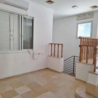 חדר עם קירות צבועים, חלונות ומעקה עץ.