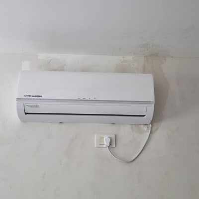 מזגן קיר לבן מותקן על קיר עם חיבור לחשמל