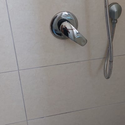 ברז מקלחת עם צינור מתכת על קיר אריחים