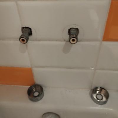 צינורות מים חשופים בקיר אריחים לבן וכתום