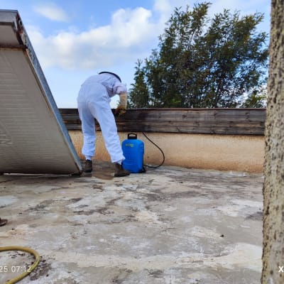 אדם בחליפת מגן מרסס חומר על גג