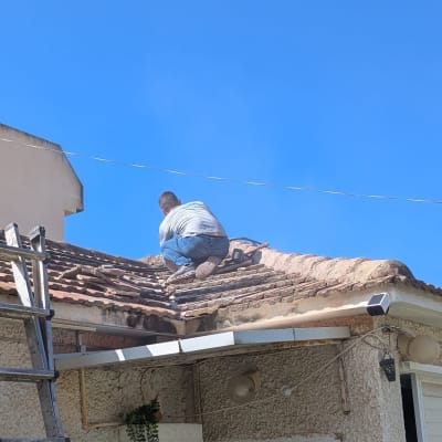 אדם עובד על גג רעפים עם סולם בצד