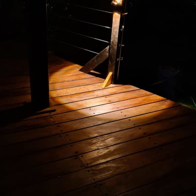 רצפת עץ מוארת עם מעקה מתכת בלילה