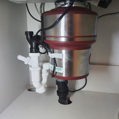 מכשיר טוחן אשפה מתחת לכיור עם צינורות חיבור