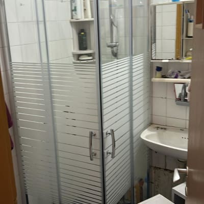 מקלחון זכוכית עם בקבוקי שמפו ומקלחת