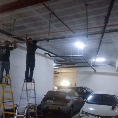 שני חשמלאים עובדים על תקרה עם סולמות