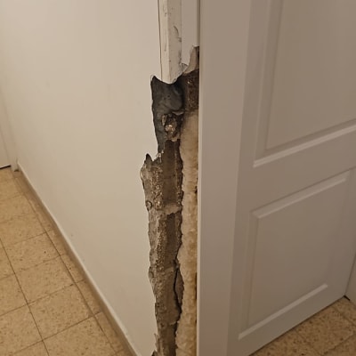 קיר פגום עם טיח מתקלף ליד דלת