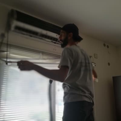 אדם מתקין מזגן על קיר פנימי בחדר