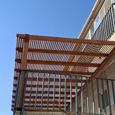 פרגולה מעץ על מרפסת עם שמיים כחולים