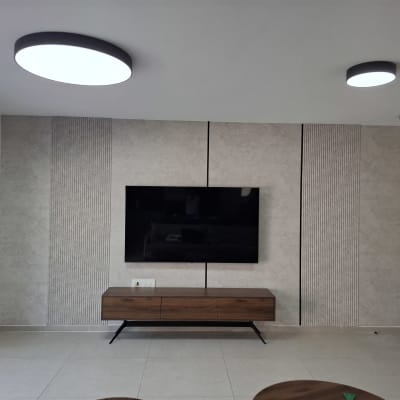 קיר עם טלוויזיה תלויה וארון עץ מתחת