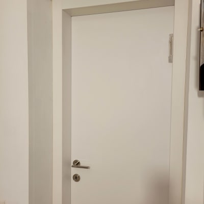 דלת לבנה עם ידית כסופה במסגרת קיר לבן