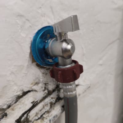 ברז מים מותקן על קיר עם צינור מחובר