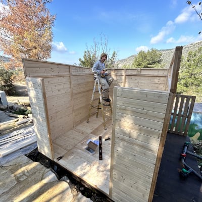 אדם על סולם עם מברגה בבניית מבנה עץ