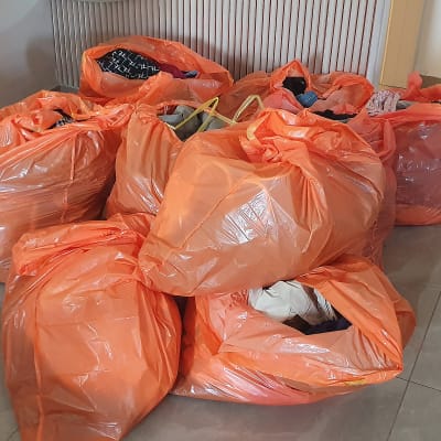 שקיות כתומות מלאות בבגדים מונחות על הרצפה