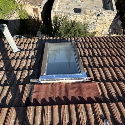 חלון גג אטום עם סרט דבק כחול על גג רעפים