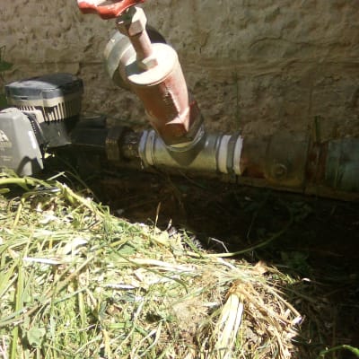 שסתום מים עם ידית אדומה וצינור מתכת