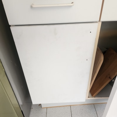 ארון מטבח לבן עם דלת פתוחה וחפצים בפנים