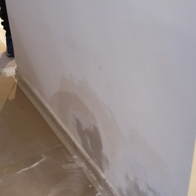 קיר עם תיקוני צבע וטיח על הרצפה