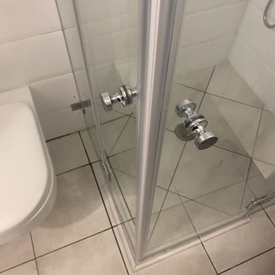 מקלחון זכוכית עם ידית מתכת ורצפת קרמיקה