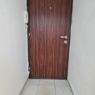 דלת עץ חומה עם ידית כסופה וקיר לבן