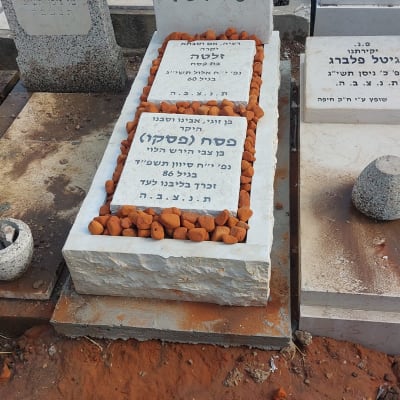 קבר עם מצבה לבנה ואבנים כתומות