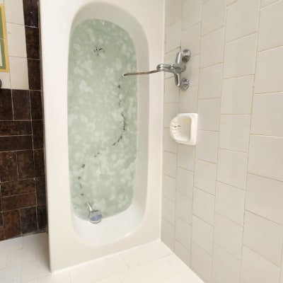 אמבטיה עם מים מוקפת באריחים חומים ולבנים