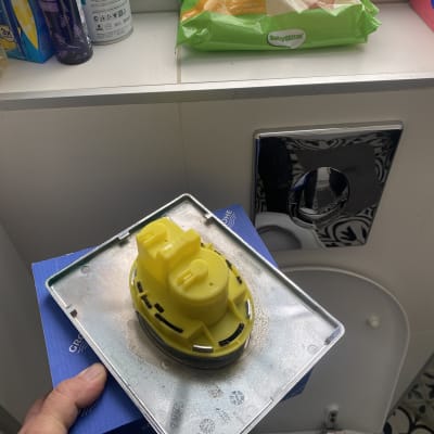 יד מחזיקה חלק צהוב של מערכת אינסטלציה בשירותים