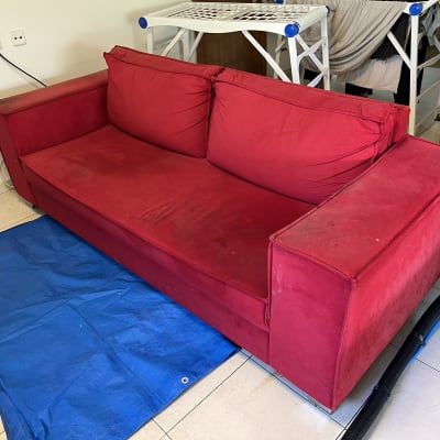 ספה אדומה עם כתמים על יריעת פלסטיק כחולה