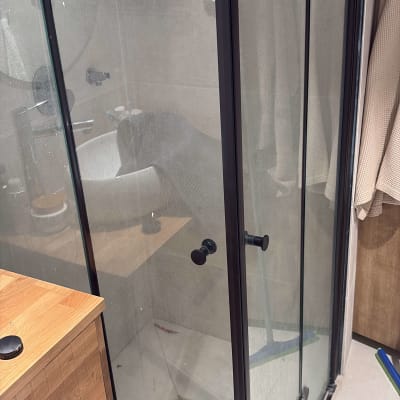 מקלחון זכוכית עם מדף מוצרים בחדר אמבטיה