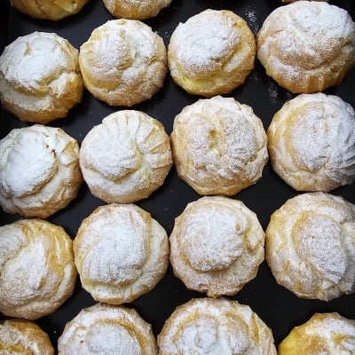 מאפים עגולים עם אבקת סוכר על מגש שחור