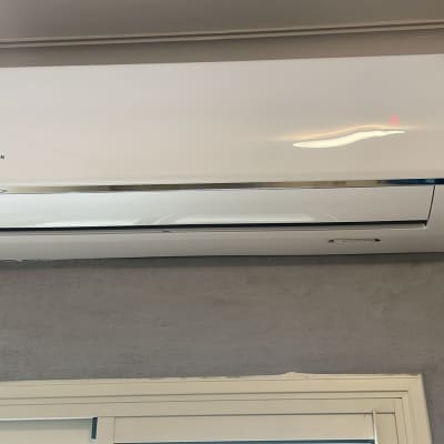 מזגן קיר לבן מותקן על קיר אפור