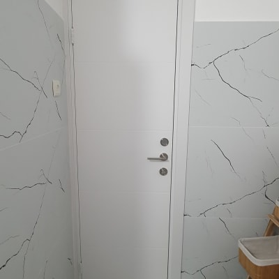 דלת לבנה עם ידית מתכת בחדר עם קירות אפורים