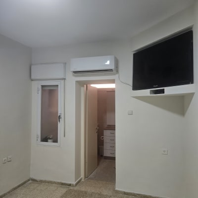 חדר עם מזגן, טלוויזיה ודלת לחדר אמבטיה