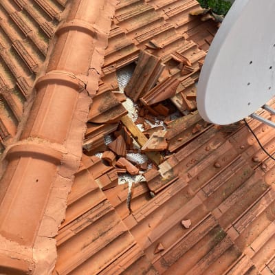 רעפים שבורים על גג עם צלחת לוויין