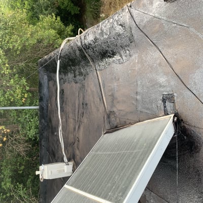 גג אטום בזפת עם קולטי שמש וחוטים