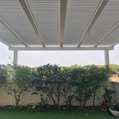 גג פרגולה לבן עם צמחייה ירוקה מסביב