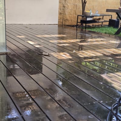משטח דק עץ רטוב בחצר בית פרטי לאחר ניקוי וחידוש