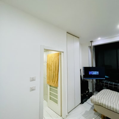 חדר עם דלת פתוחה, מגבת תלויה, מסך מחשב ומיטה.