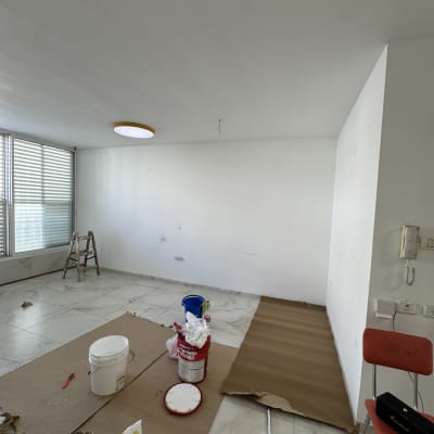 חדר עם ציוד לצביעה, כולל דלי צבע וסולם